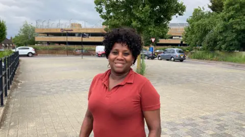 Kate Moser Andon/BBC Aida Damas standing on a pavement near the station