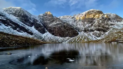 Snow-covered hills overlooking frozen Lochan a'Choire at Creag Meagaidh near Spean Bridge.