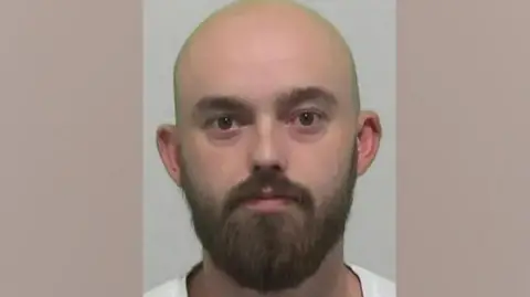 Northumbria Police A mugshot of of Kieran Usher who is bald with a full brown beard.