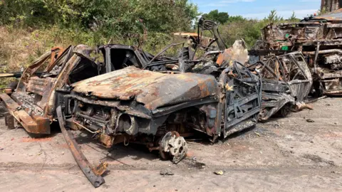 Piles of twisted blackened metal and a scorched car at the Salthouse Mills site in Barrow, which has been hit by a fire.