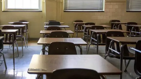 A row of tables and chairs inside a classroom.