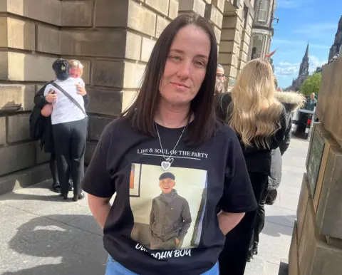 A woman with long dark dark hair wearing a black T shirt with a picture of John McNab on it