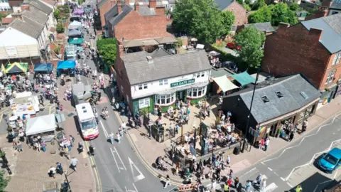 Kimberley Town Council An aerial shot of Kimberley shows a street festival with hundreds of people sitting outside a pub and pop up marquee stalls. 