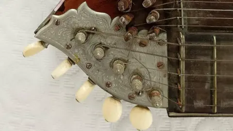 Air Ambulance Wigston There is oriental detail on the tuning posts of the instrument. The tuning section is made out of silver, while the fretboard is generally quite dirty. 