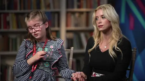 Alana holding hands with Jodie Seeley as they are being interviewed