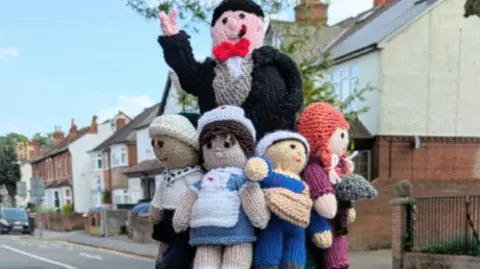 A postbox topper, featuring woollen figures including Winston Churchill and a nurse.