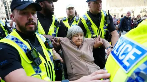 PA Media A woman being led away by police at a protest