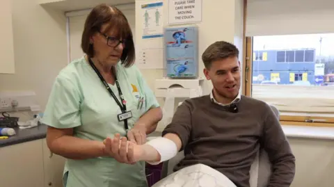 Tom has broken his arm and is having it set in plaster by a nurse at the Whitstable Medical practice. 