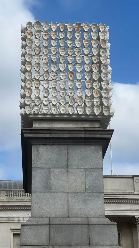 850 Improntas in situ - the plinth is topped with a cube-shaped rack covered with the facial casts of 850 people