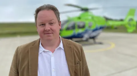 BBC A man in a brown suit looking at the camera 