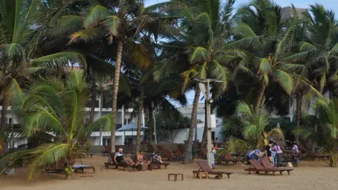 Tourists sit on the beach in Sri Lanka