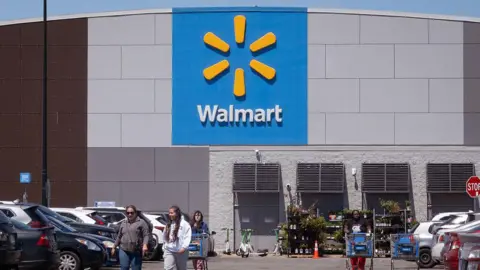 Shoppers walk through the car park after leaving a Walmart grocery store.