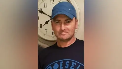 A man with a blue cap and black top