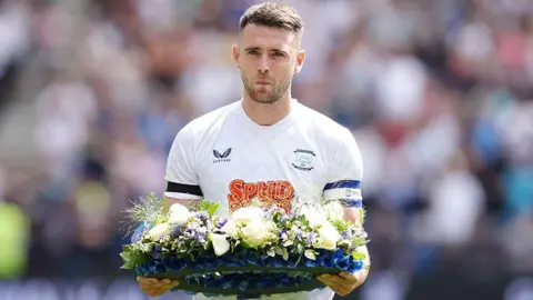 PA Media Preston North End's Ben Whiteman presents a floral wreath on the pitch in memory of Liverpool player Diogo Jota ahead of the pre-season friendly