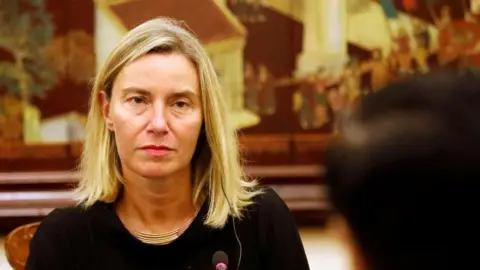 Reuters Federica Mogherini wearing a black top, an earpiece