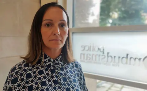 Police Ombudsman's Office a woman in a blue and white shirt standing next to a window