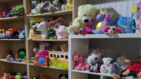 Lesley Reynolds Shelves full of childrens toys on display inside charity shop
