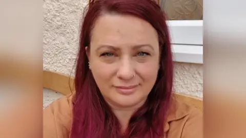 Jayne Mogg A selfie taken by Jayne Mogg showing her with long, dyed hair and a brown jacket.