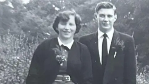 Family handout Pat and David Johnson dressed smartly looking to camera on their wedding day in 1955 in a black and white photo