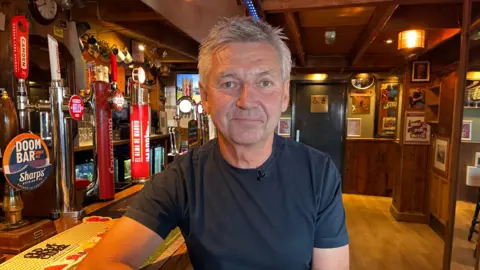Simon Jones/BBC Philip Thorley from Thorley Taverns, sat in the Barnacles pub in Margate. Philip is sat on a bar stool at the counter, with the bar visible in the background. He has greying hair and is wearing a blue t-shirt.