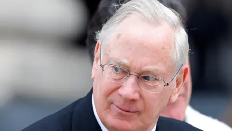 Getty Images Richard, Duke of Gloucester, wearing a dark suit and a white shirt, at a public event.