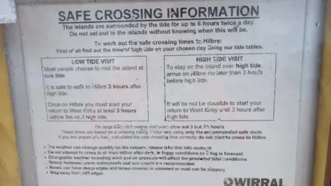 HM Coastguard A poster with the Wirral Council logo headed Safe Crossing Information has information about high and low tides including "the islands are surrounded by the tide for up to six hours twice a day". 