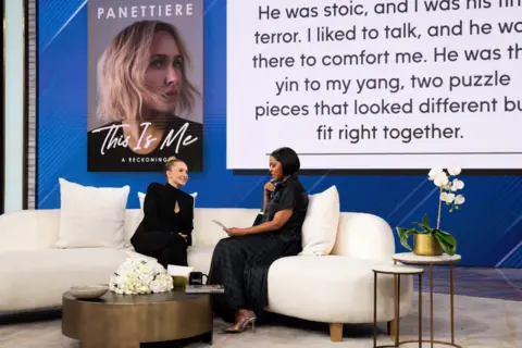 Getty Images Hayden Panettiere on a white TV show studio's sofa, speaking to the host with a graphic behind them from her book