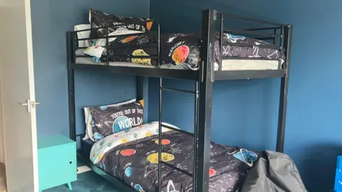 A bunk bed in a bedroom featuring bedding with planets on it