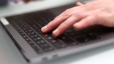 PA Media Someone using a keyboard on a laptop