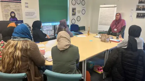 Women sit around a table listening to a tutor