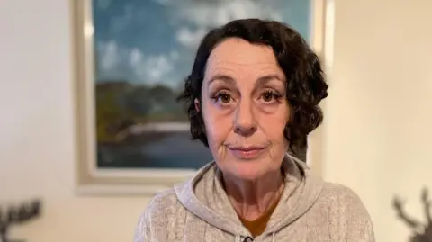 Jennifer Owen in her living room, staring expressionlessly at the camera