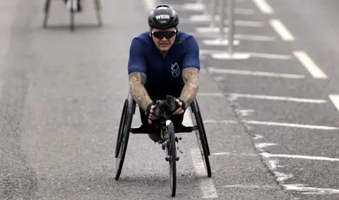 PA Media David Weir cruises over the finishing line in his wheelchair