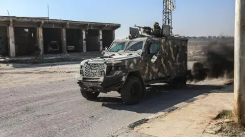 مقاتلو الأناضول المتمردين بقيادة هيئة تحرير الشام يقودون مركبة مدرعة خلال هجوم ضد القوات الحكومية في شمال غرب سوريا (28 نوفمبر 2024)