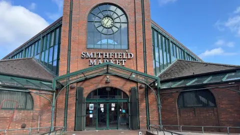 BBC The exterior of Smithfield Market. It is a red brick building with green trim