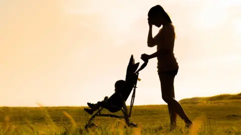 Getty Images silhouette of woman with baby in pushchair with her head in her hands