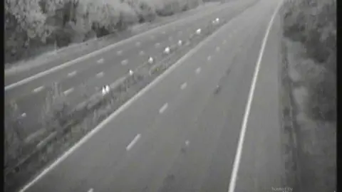 A blurry picture from a traffic camera which shows an empty motorway between junctions 12 and 13.