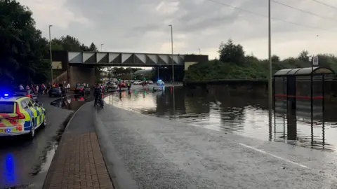 Police car and a flooded road with a car trapped