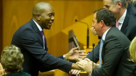 Gallo via Getty Images Mmusi Maimane and John Steenhuisen, then both members of the Democratic Alliance, shake hands in South Africa's parliament