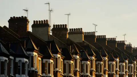 A row of terraced brick houses with chimneys and television aerials.
