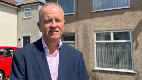 Sean Fudge who works at South Gloucestershire Council stood outside an empty home which has its curtains closed. 