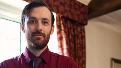 Supplied A man in a red shirt and tie