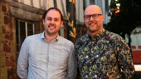 Supplied Two men in patterned shirts look at the camera