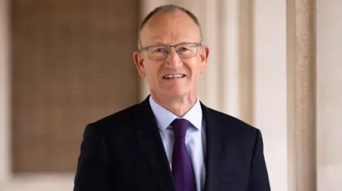 Hertfordshire County Council A picture of Hertfordshire County Council Leader Richard Roberts in a black jacket with a dark purple tie.