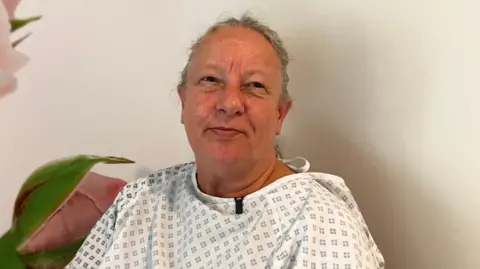 Vanda Instone in a hospital gown looking at the camera