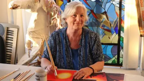 Independence Trust Woman sits at a table holding a paintbrush