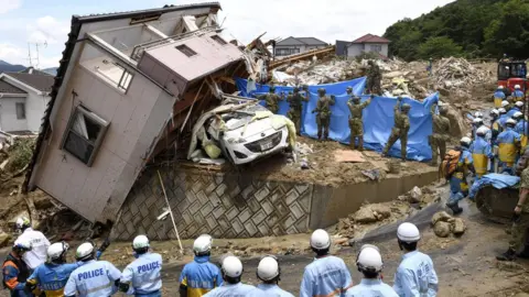 Reuters Police and Ground Self-Defense Force's rescue workers inspect damage caused by heavy rains in Kumano, Hiroshima Prefecture, Japan, 09 July 2018.