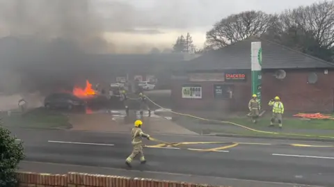 Other Five fire fighters with hoses tackle the fire at the BP petrol station
