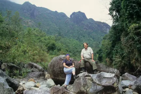 Bleddyn and Sue Wynn Jones Bleddyn and Sue Wynn Jones. Sue is stood in front of a boulder and Bleddyn is sat on one