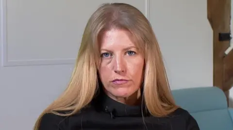 Donna Jones, a woman with long blonde hair and blue eyes, is pictured looking at the camera. She is wearing a dark jumper. 