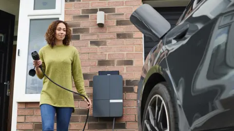 Woman charging an electric car outside her house